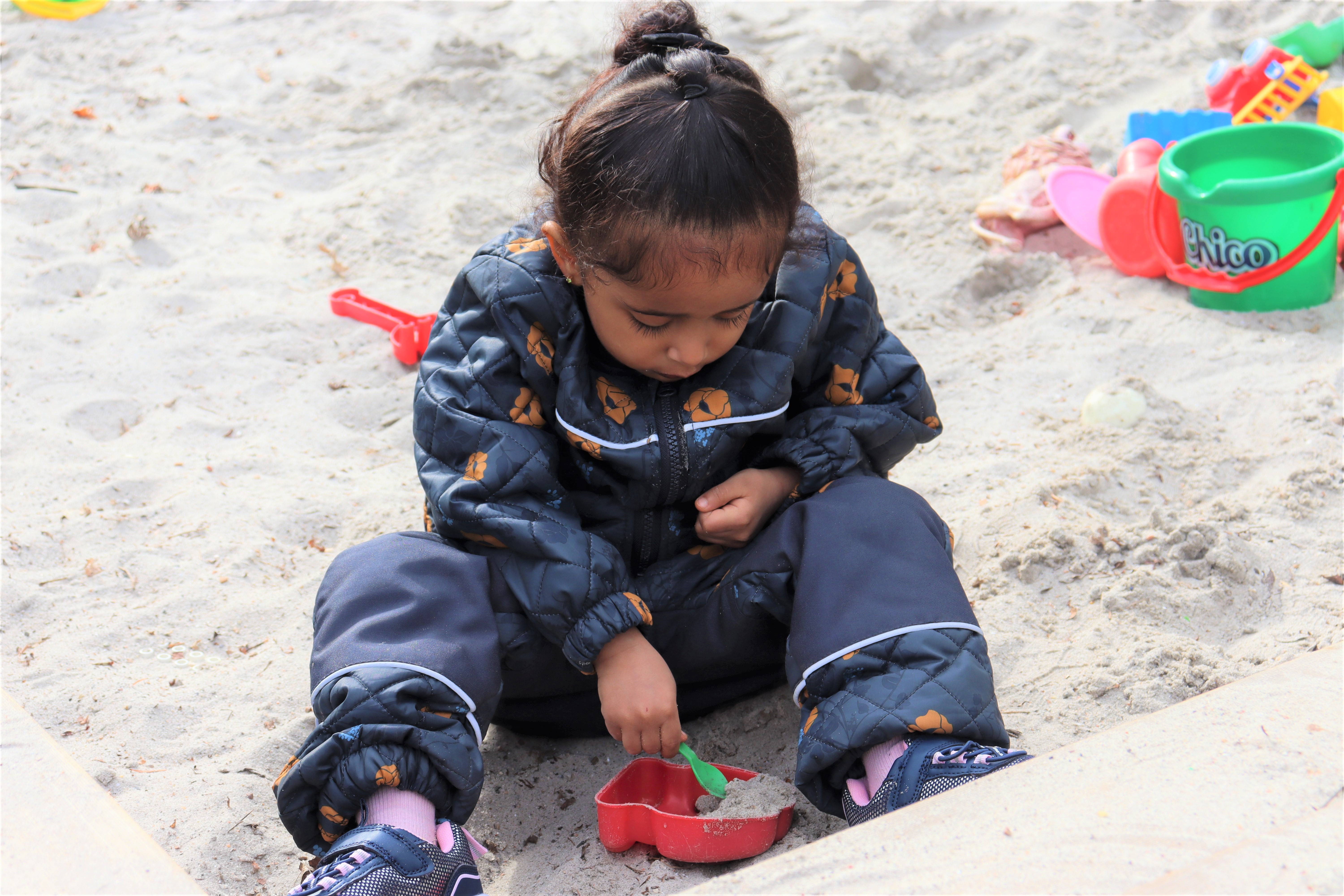 Barn leger i sandkasse og graver